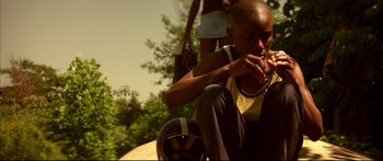 Movie still from “George Washington” (2000), directed by David Gordon Green – A young man sitting on top of a skate board; Medium shot, Low angle