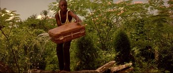 Movie still from “George Washington” (2000), directed by David Gordon Green – A man holding a suitcase in a forest; Medium shot, High angle