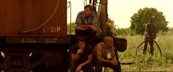 Movie still from “George Washington” (2000), directed by David Gordon Green – A group of men sitting on top of a train car; Medium shot, Low angle