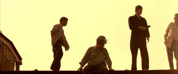 Movie still from “George Washington” (2000), directed by David Gordon Green – Two men are sitting on a wall and one is sitting on the ground and the other is sitting on the ground; Wide shot, Low angle