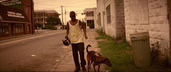 Movie still from “George Washington” (2000), directed by David Gordon Green – A man walking a dog down a sidewalk; Wide shot, Low angle
