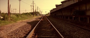 Movie still from “George Washington” (2000), directed by David Gordon Green – A train track that has some buildings in the background; Extreme Wide shot, High angle