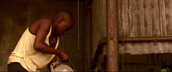 Movie still from “George Washington” (2000), directed by David Gordon Green – A young boy is pouring water into a pot; Medium shot, Low angle
