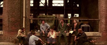 Movie still from “George Washington” (2000), directed by David Gordon Green – A group of men sitting next to each other on a brick wall; Wide shot, High angle