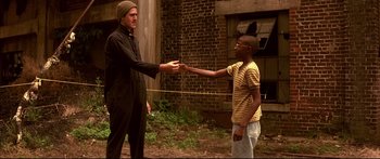 Movie still from “George Washington” (2000), directed by David Gordon Green – Two men are shaking hands in an open area; Medium shot, Low angle