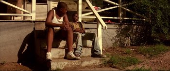 Movie still from “George Washington” (2000), directed by David Gordon Green – Two young men sitting on a porch with their arms crossed; Wide shot, Low angle