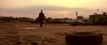 Movie still from “George Washington” (2000), directed by David Gordon Green – A man walking across a dirt field at sunset; Extreme Wide shot, Low angle