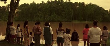 Movie still from “George Washington” (2000), directed by David Gordon Green – A group of people standing in a body of water near a forest; Extreme Wide shot, High angle