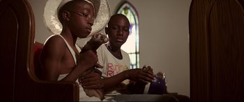 Movie still from “George Washington” (2000), directed by David Gordon Green – Two people sitting at a table holding a ferret; Close Up shot, Low angle