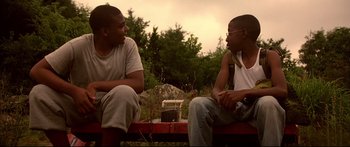 Movie still from “George Washington” (2000), directed by David Gordon Green – Two young men sitting on a bench talking; Medium shot, Low angle