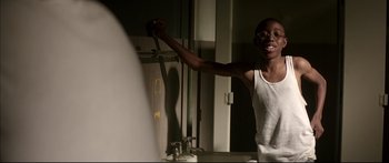 Movie still from “George Washington” (2000), directed by David Gordon Green – A young man in a white tank top is in a bathroom; Medium shot, Low angle