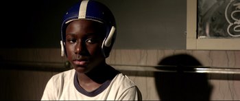 Movie still from “George Washington” (2000), directed by David Gordon Green – A young man wearing a football helmet and looking at the camera; Close Up shot, Low angle