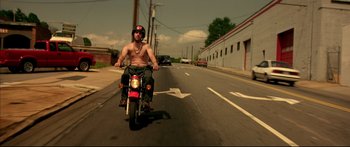 Movie still from “George Washington” (2000), directed by David Gordon Green – A man riding a motorcycle down a street; Wide shot, Low angle