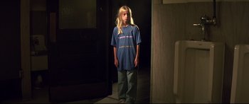 Movie still from “George Washington” (2000), directed by David Gordon Green – A young girl standing in a dark room with her hands in her pockets; Medium shot, Low angle