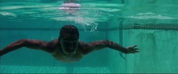 Movie still from “George Washington” (2000), directed by David Gordon Green – A man is swimming in a pool under the water; Close Up shot, Overhead angle