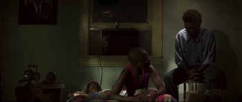Movie still from “George Washington” (2000), directed by David Gordon Green – Two young people sitting on a bed in front of a television; Medium shot, Over the shoulder angle