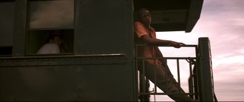 Movie still from “George Washington” (2000), directed by David Gordon Green – A man standing on top of a metal railing next to stairs; Medium shot, Low angle