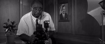 Movie still from “George Washington” (2000), directed by David Gordon Green – A man holding a camera in front of a picture of a man; Close Up shot, Low angle