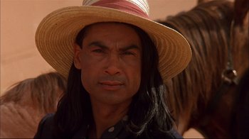 Movie still from “Geronimo: An American Legend” (1993), directed by Walter Hill – A person with long hair wearing a hat; Close Up shot, Over the shoulder angle