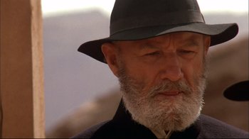 Movie still from “Geronimo: An American Legend” (1993), directed by Walter Hill – An old man with a gray beard wearing a black hat; Close Up shot, Low angle