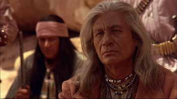 Movie still from “Geronimo: An American Legend” (1993), directed by Walter Hill – An older man with long hair and a beard; Close Up shot, Over the shoulder angle