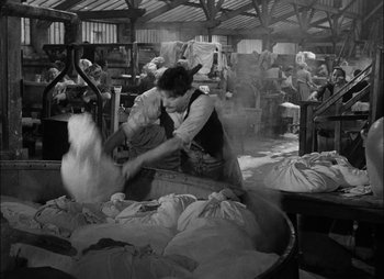 Movie still from “Gervaise” (1956), directed by René Clément – An old photo of a woman working in a factory; Wide shot, High angle