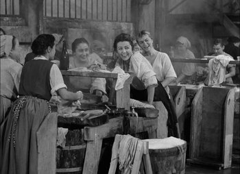 Movie still from “Gervaise” (1956), directed by René Clément – A black and white photo of a group of people cooking food; Wide shot, High angle