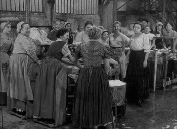 Movie still from “Gervaise” (1956), directed by René Clément – A group of people standing around in a room; Wide shot, High angle