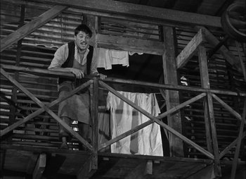 Movie still from “Gervaise” (1956), directed by René Clément – A man standing on top of a wooden platform; Wide shot, Low angle