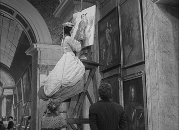 Movie still from “Gervaise” (1956), directed by René Clément – A woman in a white dress is painting a picture; Wide shot, Low angle