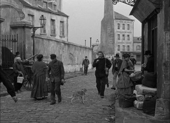 Movie still from “Gervaise” (1956), directed by René Clément – A black and white photo of people walking down a street; Wide shot, Over the shoulder angle