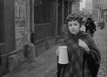 Movie still from “Gervaise” (1956), directed by René Clément – A woman holding a cup of coffee in her hand; Medium shot, High angle