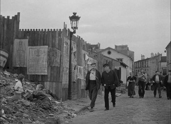 Movie still from “Gervaise” (1956), directed by René Clément – A group of people walking down a street; Wide shot, High angle