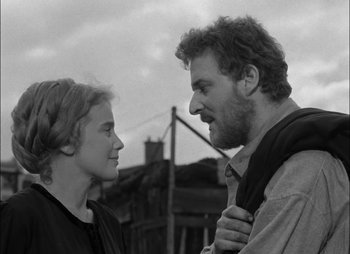 Movie still from “Gervaise” (1956), directed by René Clément – A man and a woman standing next to each other in front of a building; Close Up shot, Low angle