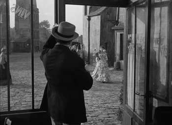Movie still from “Gervaise” (1956), directed by René Clément – An old photo of a man and a woman walking in the street; Wide shot, Over the shoulder angle