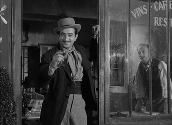 Movie still from “Gervaise” (1956), directed by René Clément – A black and white photo of a man in a suit and hat; Medium shot, Low angle