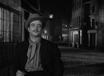 Movie still from “Gervaise” (1956), directed by René Clément – A black and white photo of a man wearing a hat; Medium shot, Low angle