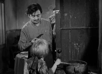 Movie still from “Gervaise” (1956), directed by René Clément – A man and a boy are cooking in an old - fashioned kitchen; Medium shot, High angle