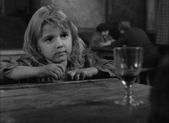 Movie still from “Gervaise” (1956), directed by René Clément – A little girl sitting at a table with a glass of wine; Close Up shot, High angle