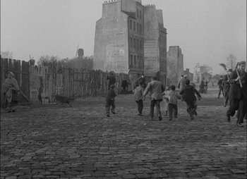 Movie still from “Gervaise” (1956), directed by René Clément – A black and white photo of a group of children running on a cobblestone street; Extreme Wide shot, High angle