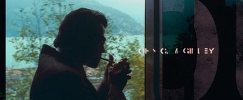 Movie still from “Get Carter” (2000), directed by Stephen Kay – A man smoking a cigarette while looking out a window; Medium shot, Over the shoulder angle