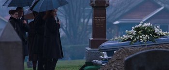 Movie still from “Get Carter” (2000), directed by Stephen Kay – A woman holding an umbrella standing next to a grave; Wide shot, Over the shoulder angle