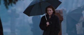 Movie still from “Get Carter” (2000), directed by Stephen Kay – A woman holding an umbrella while standing on a sidewalk; Medium shot, Low angle