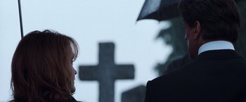 Movie still from “Get Carter” (2000), directed by Stephen Kay – Two people standing under an umbrella in front of a cross; Close Up shot, Over the shoulder angle
