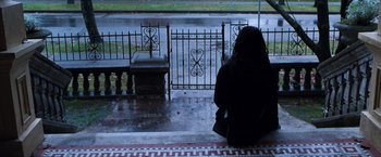Movie still from “Get Carter” (2000), directed by Stephen Kay – A woman sitting on a bench in the rain next to an iron fence; Wide shot, High angle