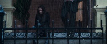 Movie still from “Get Carter” (2000), directed by Stephen Kay – A woman sitting on a bench in the pouring rain; Wide shot, Low angle