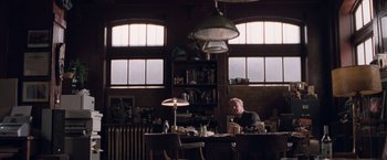 Movie still from “Get Carter” (2000), directed by Stephen Kay – A man sitting at a table in front of a lamp; Wide shot, Low angle