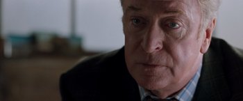 Movie still from “Get Carter” (2000), directed by Stephen Kay – An older man in a suit and tie looking at the camera; Close Up shot, Over the shoulder angle