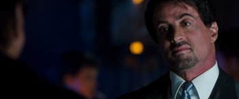 Movie still from “Get Carter” (2000), directed by Stephen Kay – A man in a dark room with lights in the background; Close Up shot, Over the shoulder angle