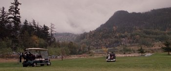 Movie still from “Get Carter” (2000), directed by Stephen Kay – A person riding a motorcycle in a field with trees in the background; Extreme Wide shot, High angle